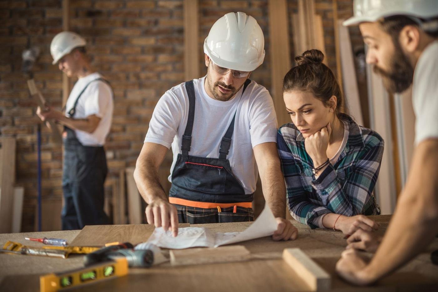 Builder and homeowners reviewing plans on site